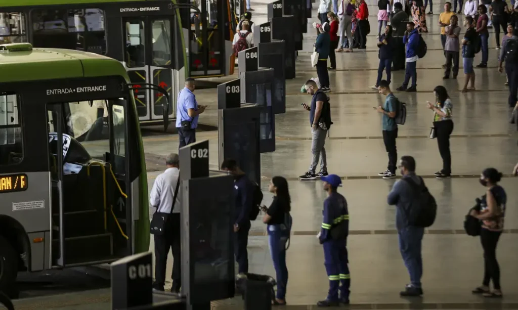 Brasília (DF), 09/08/2023 - Movimentação de passageiros e ônibus na Rodoviária do Plano Piloto. Nos dias 8 e 9 de agosto acontece, em Brasília, o 36º Seminário Nacional de Transporte Urbano, em que empresários, entidades de classe, especialistas e representantes de governo debatem as mudanças necessárias no setor. Foto: Marcelo Camargo/Agência Brasil© Marcelo Camargo/Agência Brasil Versão em áudio A auxiliar de serviços gerais Núbia Sales Veras, de 52 anos, moradora da Cidade Ocidental, município goiano no Entorno do Distrito Federal, utiliza diariamente o transporte público para cruzar o limite com a capital do país e chegar até a empresa onde trabalha, no Lago Sul, bairro de elite de Brasília, a cerca de 50 quilômetros (km) de casa. A distância, o custo da tarifa do ônibus e a baixa qualidade do transporte urbano criam limitações para que ela acesse serviços essenciais da sua vida, como o tratamento que faz para fibromialgia, uma síndrome crônica que causa dores musculares e articulares em várias partes do corpo. "Já perdi compromisso, já perdi consulta do meu tratamento no [hospital] Sarah [instituição de saúde focada em reabilitação motora e neurológica], tudo por causa da demora do ônibus e do valor da passagem", contou à Agência Brasil. A reportagem conversou com Núbia, na tarde da última sexta-feira (12), quando ela passava pela Rodoviária do Plano Piloto, o principal terminal de transporte público urbano do Distrito Federal e região metropolitana, localizada no centro da capital do país. Outro problema relatado pela trabalhadora é o valor da passagem, que chega a custar R$ 18 por dia, custo que limita sua vida social. Brasília (DF), 13/06/2026 - Núbia Sales Veras fala sobre tarifa zero pode garantir mais acesso a serviços de saúde. Foto: Pedro Rafael Vilela/Agência Brasil Núbia afirma que filhas perderam oportunidades por causa do preço da passagem. Foto: Pedro Rafael Vilela/Agência Brasil "Muitas vezes não pude utilizar para a cultura, para colocar minhas filhas em uma escola melhor, mas mais distante, por causa desse valor da passagem", afirmou. A experiência de Núbia, bem como de milhares de pessoas que usam o transporte público rodoviário para transitar pelas grandes cidades do país, reflete as conclusões de um novo estudo desenvolvido por pesquisadores vinculados ao Instituto de Ciência Polícia da Universidade de Brasília (UnB). O artigo intitulado Quem pode circular? Tarifa zero, mobilidade e desigualdades raciais no acesso à cidade e aos serviços aponta que o custo tarifário e a precariedade do transporte, incluindo superlotação, insegurança e imprevisibilidade, geram obstáculos concretos à continuidade do cuidado em saúde, resultando no atraso de diagnósticos, faltas a consultas agendadas e prejuízos no acompanhamento preventivo de doenças crônicas. Racismo estrutural O texto, publicado no formato policy paper (um tipo de relatório técnico), destaca que os tempos de deslocamento prolongados em regiões metropolitanas "atuam como severos agravantes de sofrimento psíquico, estresse crônico e exaustão, potencializando quadros de ansiedade e depressão". Esses efeitos, de acordo com a pesquisa, tendem a ser particularmente significativos quando observados sob a perspectiva das desigualdades raciais. Isso porque a população negra está sobrerrepresentada entre os grupos de menor renda, residentes em territórios periféricos e mais dependentes do transporte público. "Isso significa que as barreiras econômicas e territoriais à mobilidade incidem de forma desproporcional sobre essa população, limitando seu acesso à cidade e aos seus serviços", aponta o estudo. Também na Rodoviária do Plano Piloto, a aposentada Helena Simão, mulher negra de 72 anos, caminhava devagar e com dificuldade quando parou para conversar com a reportagem, pouco antes de embarcar no ônibus para chegar a Samambaia, região administrativa do DF, distante cerca de 30 quilômetros do centro da capital. Ela contou que convive há anos com osteoporose, uma doença que reduz a densidade e enfraquece os ossos do corpo. Apesar de não pagar mais a tarifa, por ter gratuidade de pessoa idosa, Helena reclama da baixa circulação de ônibus na periferia. Brasília (DF), 13/06/2026 - Helena Simão fala sobre tarifa zero pode garantir mais acesso a serviços de saúde. Foto: Pedro Rafael Vilela/Agência Brasil Helena Simão não paga mais passagem, mas lamenta a pouca frequência de ônibus na periferia Foto: Pedro Rafael Vilela/Agência Brasil "Eu já não pago o transporte, mas demora muito para passar e já perdi consulta médica", denunciou Helena. Dados do DataSUS citados na pesquisa demonstram, por exemplo, que mulheres negras enfrentam o dobro do risco de morte materna em relação a mulheres brancas, "uma disparidade que se conecta diretamente às restrições materiais e espaciais de locomoção impostas pela segregação urbana". >>Livro debate tarifa zero e mobilidade urbana como qualidade de vida Transporte universal Um dos focos do estudo é demonstrar que a remoção da principal barreira econômica ao transporte público, que é o custo da tarifa, por meio da implantação da tarifa zero universal, tem potencial para atuar como uma política estruturante de redução de desigualdades, indo muito além de uma simples medida de transporte público. "Tem potencial de transformar a relação da sociedade com uma política pública, tal qual o Sistema Único de Saúde (SUS) propiciou, mas agora do ponto de vista do transporte", observa Paíque Duques Santarém, pesquisador da UnB (Universidade de Brasília) e um dos autores do artigo. Essa desoneração integral do custo da tarifa, na análise dos pesquisadores, constituiria uma ferramenta estratégica para garantir o acesso efetivo aos equipamentos públicos, assegurar a continuidade do cuidado terapêutico e "tensionar, de forma definitiva, os padrões históricos de exclusão territorial e racial que fragmentam as cidades brasileiras". © Marcelo Camargo/Agência Brasil