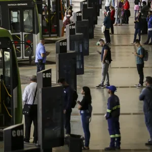 Brasília (DF), 09/08/2023 - Movimentação de passageiros e ônibus na Rodoviária do Plano Piloto. Nos dias 8 e 9 de agosto acontece, em Brasília, o 36º Seminário Nacional de Transporte Urbano, em que empresários, entidades de classe, especialistas e representantes de governo debatem as mudanças necessárias no setor. Foto: Marcelo Camargo/Agência Brasil© Marcelo Camargo/Agência Brasil Versão em áudio A auxiliar de serviços gerais Núbia Sales Veras, de 52 anos, moradora da Cidade Ocidental, município goiano no Entorno do Distrito Federal, utiliza diariamente o transporte público para cruzar o limite com a capital do país e chegar até a empresa onde trabalha, no Lago Sul, bairro de elite de Brasília, a cerca de 50 quilômetros (km) de casa. A distância, o custo da tarifa do ônibus e a baixa qualidade do transporte urbano criam limitações para que ela acesse serviços essenciais da sua vida, como o tratamento que faz para fibromialgia, uma síndrome crônica que causa dores musculares e articulares em várias partes do corpo. "Já perdi compromisso, já perdi consulta do meu tratamento no [hospital] Sarah [instituição de saúde focada em reabilitação motora e neurológica], tudo por causa da demora do ônibus e do valor da passagem", contou à Agência Brasil. A reportagem conversou com Núbia, na tarde da última sexta-feira (12), quando ela passava pela Rodoviária do Plano Piloto, o principal terminal de transporte público urbano do Distrito Federal e região metropolitana, localizada no centro da capital do país. Outro problema relatado pela trabalhadora é o valor da passagem, que chega a custar R$ 18 por dia, custo que limita sua vida social. Brasília (DF), 13/06/2026 - Núbia Sales Veras fala sobre tarifa zero pode garantir mais acesso a serviços de saúde. Foto: Pedro Rafael Vilela/Agência Brasil Núbia afirma que filhas perderam oportunidades por causa do preço da passagem. Foto: Pedro Rafael Vilela/Agência Brasil "Muitas vezes não pude utilizar para a cultura, para colocar minhas filhas em uma escola melhor, mas mais distante, por causa desse valor da passagem", afirmou. A experiência de Núbia, bem como de milhares de pessoas que usam o transporte público rodoviário para transitar pelas grandes cidades do país, reflete as conclusões de um novo estudo desenvolvido por pesquisadores vinculados ao Instituto de Ciência Polícia da Universidade de Brasília (UnB). O artigo intitulado Quem pode circular? Tarifa zero, mobilidade e desigualdades raciais no acesso à cidade e aos serviços aponta que o custo tarifário e a precariedade do transporte, incluindo superlotação, insegurança e imprevisibilidade, geram obstáculos concretos à continuidade do cuidado em saúde, resultando no atraso de diagnósticos, faltas a consultas agendadas e prejuízos no acompanhamento preventivo de doenças crônicas. Racismo estrutural O texto, publicado no formato policy paper (um tipo de relatório técnico), destaca que os tempos de deslocamento prolongados em regiões metropolitanas "atuam como severos agravantes de sofrimento psíquico, estresse crônico e exaustão, potencializando quadros de ansiedade e depressão". Esses efeitos, de acordo com a pesquisa, tendem a ser particularmente significativos quando observados sob a perspectiva das desigualdades raciais. Isso porque a população negra está sobrerrepresentada entre os grupos de menor renda, residentes em territórios periféricos e mais dependentes do transporte público. "Isso significa que as barreiras econômicas e territoriais à mobilidade incidem de forma desproporcional sobre essa população, limitando seu acesso à cidade e aos seus serviços", aponta o estudo. Também na Rodoviária do Plano Piloto, a aposentada Helena Simão, mulher negra de 72 anos, caminhava devagar e com dificuldade quando parou para conversar com a reportagem, pouco antes de embarcar no ônibus para chegar a Samambaia, região administrativa do DF, distante cerca de 30 quilômetros do centro da capital. Ela contou que convive há anos com osteoporose, uma doença que reduz a densidade e enfraquece os ossos do corpo. Apesar de não pagar mais a tarifa, por ter gratuidade de pessoa idosa, Helena reclama da baixa circulação de ônibus na periferia. Brasília (DF), 13/06/2026 - Helena Simão fala sobre tarifa zero pode garantir mais acesso a serviços de saúde. Foto: Pedro Rafael Vilela/Agência Brasil Helena Simão não paga mais passagem, mas lamenta a pouca frequência de ônibus na periferia Foto: Pedro Rafael Vilela/Agência Brasil "Eu já não pago o transporte, mas demora muito para passar e já perdi consulta médica", denunciou Helena. Dados do DataSUS citados na pesquisa demonstram, por exemplo, que mulheres negras enfrentam o dobro do risco de morte materna em relação a mulheres brancas, "uma disparidade que se conecta diretamente às restrições materiais e espaciais de locomoção impostas pela segregação urbana". >>Livro debate tarifa zero e mobilidade urbana como qualidade de vida Transporte universal Um dos focos do estudo é demonstrar que a remoção da principal barreira econômica ao transporte público, que é o custo da tarifa, por meio da implantação da tarifa zero universal, tem potencial para atuar como uma política estruturante de redução de desigualdades, indo muito além de uma simples medida de transporte público. "Tem potencial de transformar a relação da sociedade com uma política pública, tal qual o Sistema Único de Saúde (SUS) propiciou, mas agora do ponto de vista do transporte", observa Paíque Duques Santarém, pesquisador da UnB (Universidade de Brasília) e um dos autores do artigo. Essa desoneração integral do custo da tarifa, na análise dos pesquisadores, constituiria uma ferramenta estratégica para garantir o acesso efetivo aos equipamentos públicos, assegurar a continuidade do cuidado terapêutico e "tensionar, de forma definitiva, os padrões históricos de exclusão territorial e racial que fragmentam as cidades brasileiras". © Marcelo Camargo/Agência Brasil